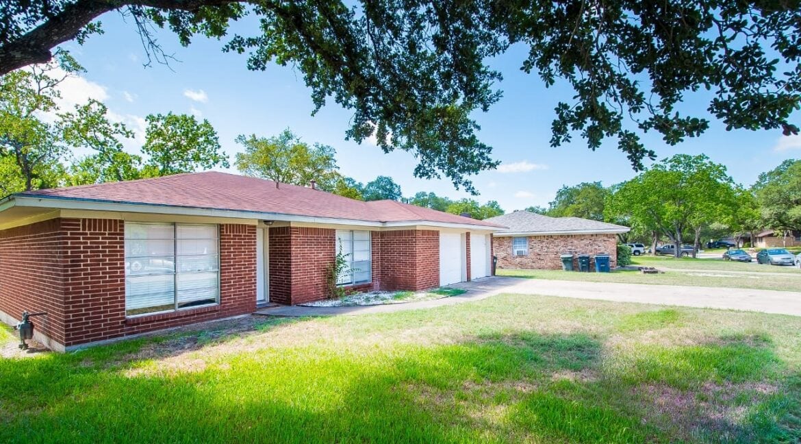 Single-story brick house with a large front yard and trees in Aggieland Leasing's service area.