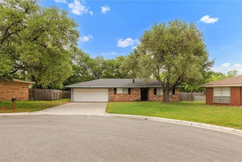 Single-story brick house with two large trees in front, located on Timm Drive.