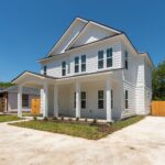 New white two-story house with front porch and driveway in Aggieland, Texas.