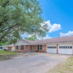 Single-story brick house with attached garage and large front yard in Aggieland.