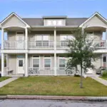 Front view of a two-story residential building with balconies in Aggieland, Texas.