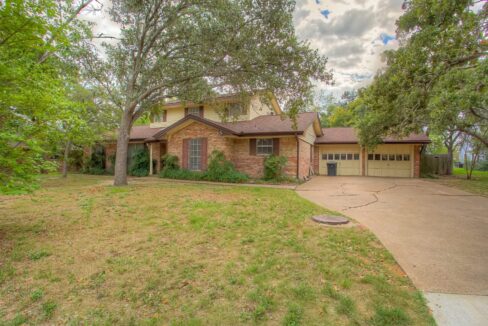 Front view of a brick house with a two-car garage and a curved driveway in Aggieland, Texas.