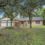Brick house with attached garage and large front yard with trees in College Station, TX.