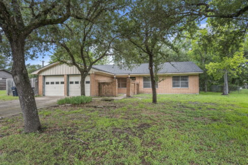 Brick house with attached garage and large front yard with trees in College Station, TX.