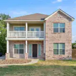 Two-story brick suburban home with a front porch and balcony, in Aggieland area.