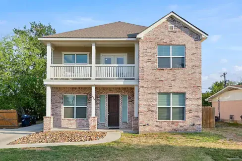 Two-story brick suburban home with a front porch and balcony, in Aggieland area.