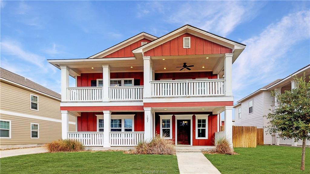 Red two-story house with white porch railings and a front yard in Aggieland, Texas.